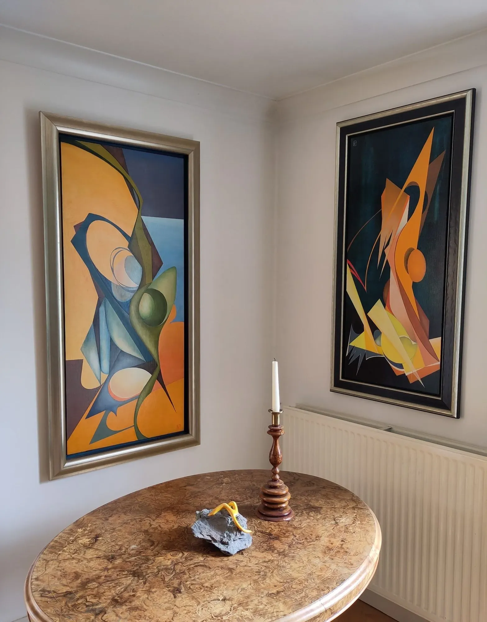 Earth's Embrace hanging at home beside Flame Dance, two framed abstract oils by Bruce Thomson in the corner of a room