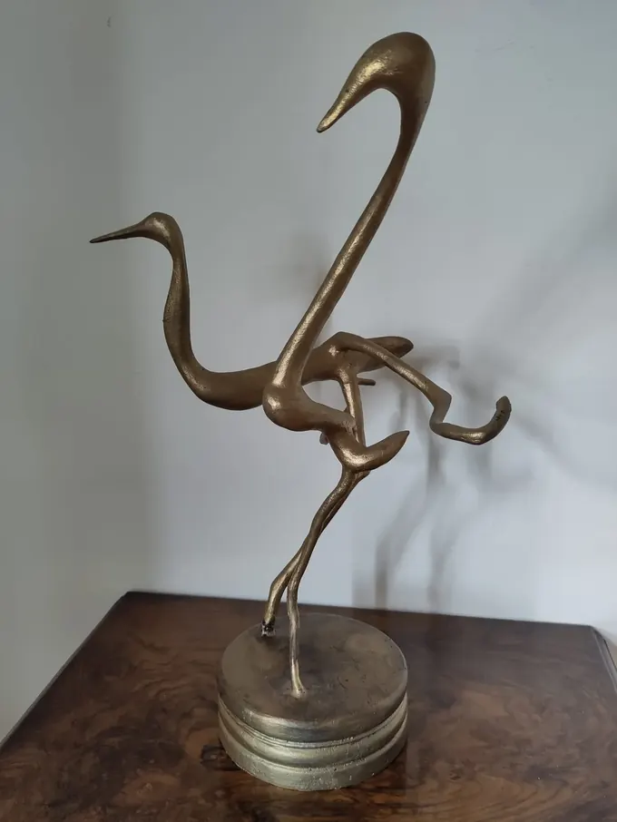 Dancing Cranes, a gilt-finished bronze by Bruce Thomson of two cranes with necks turned and legs crossed mid-step