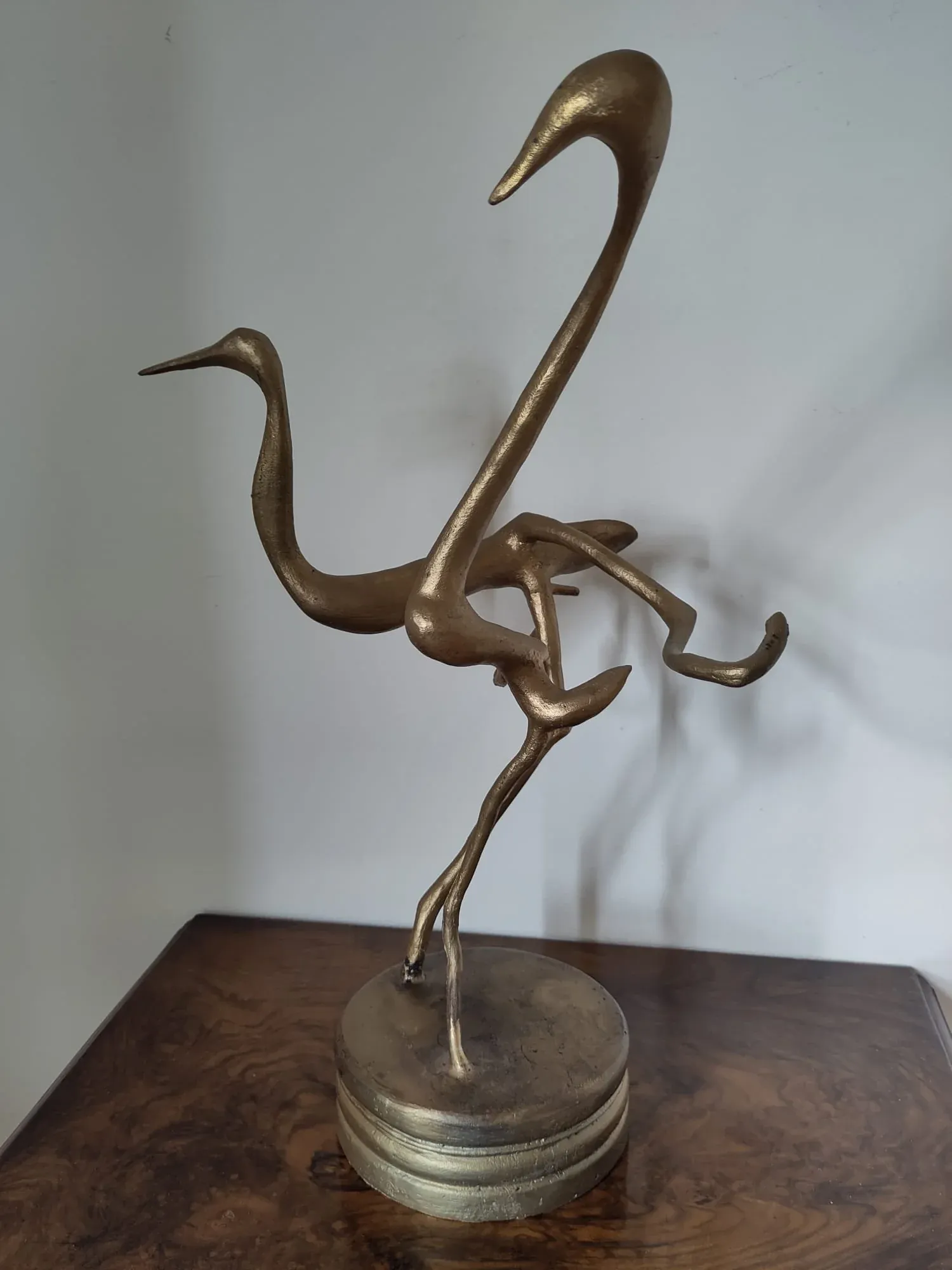 Dancing Cranes, a gilt-finished bronze by Bruce Thomson of two cranes with necks turned and legs crossed mid-step